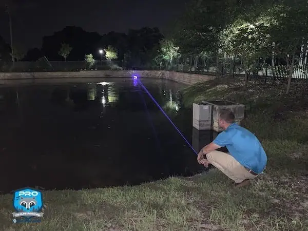 Pro Wildlife Removal technician working beside a pond at night