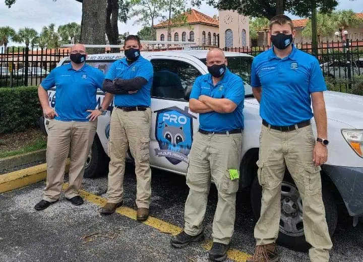 Pro Wildlife Removal team in uniform beside a company truck